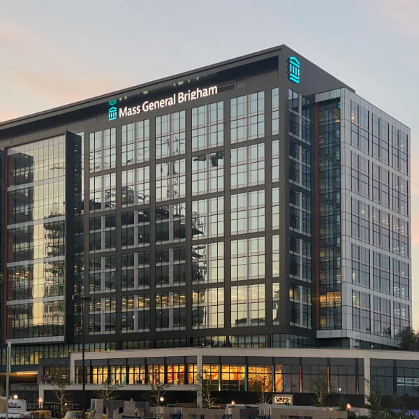 Exterior of the Mass General Brigham building at sunset.